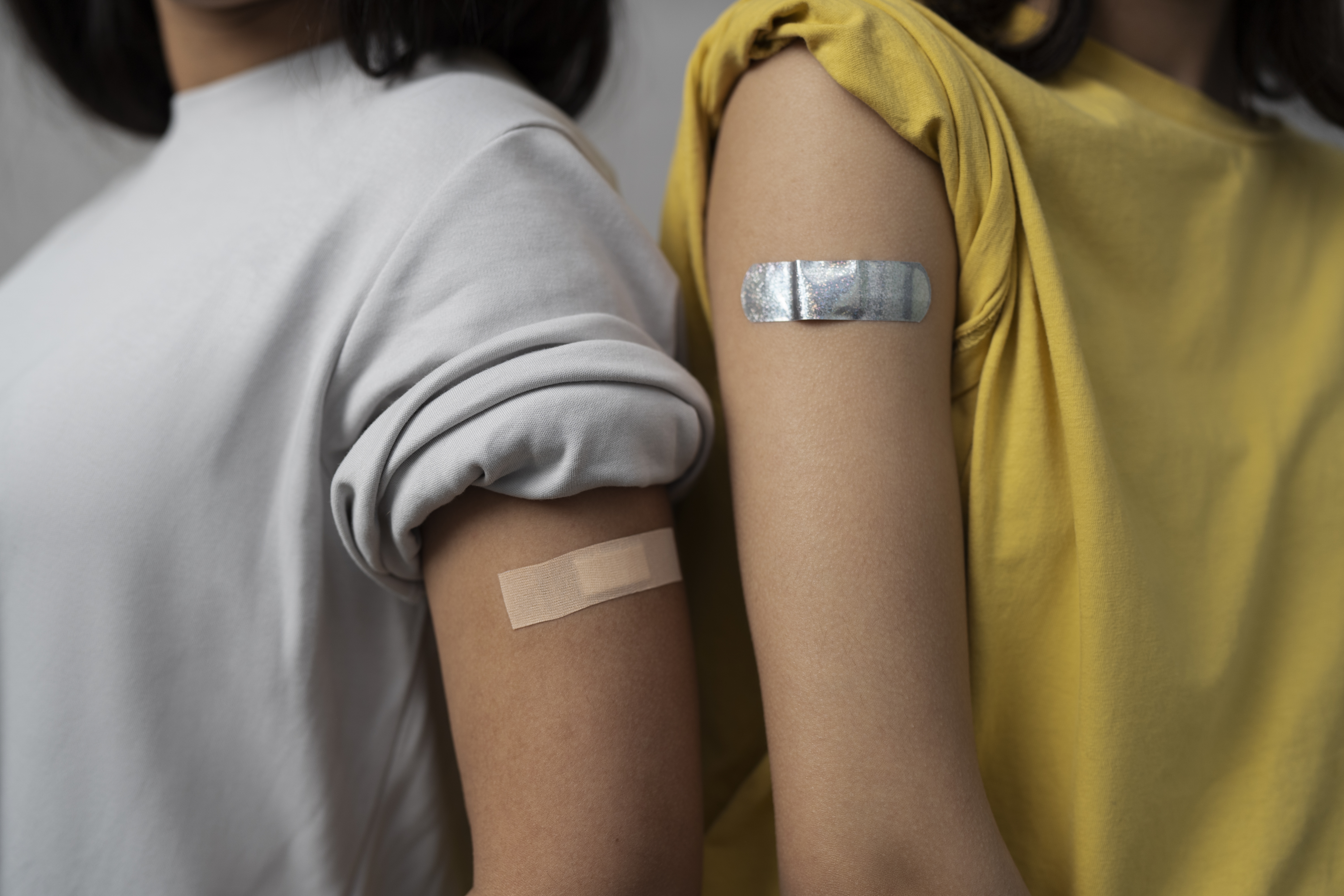 Two arms showing adhesive bandages after vaccination