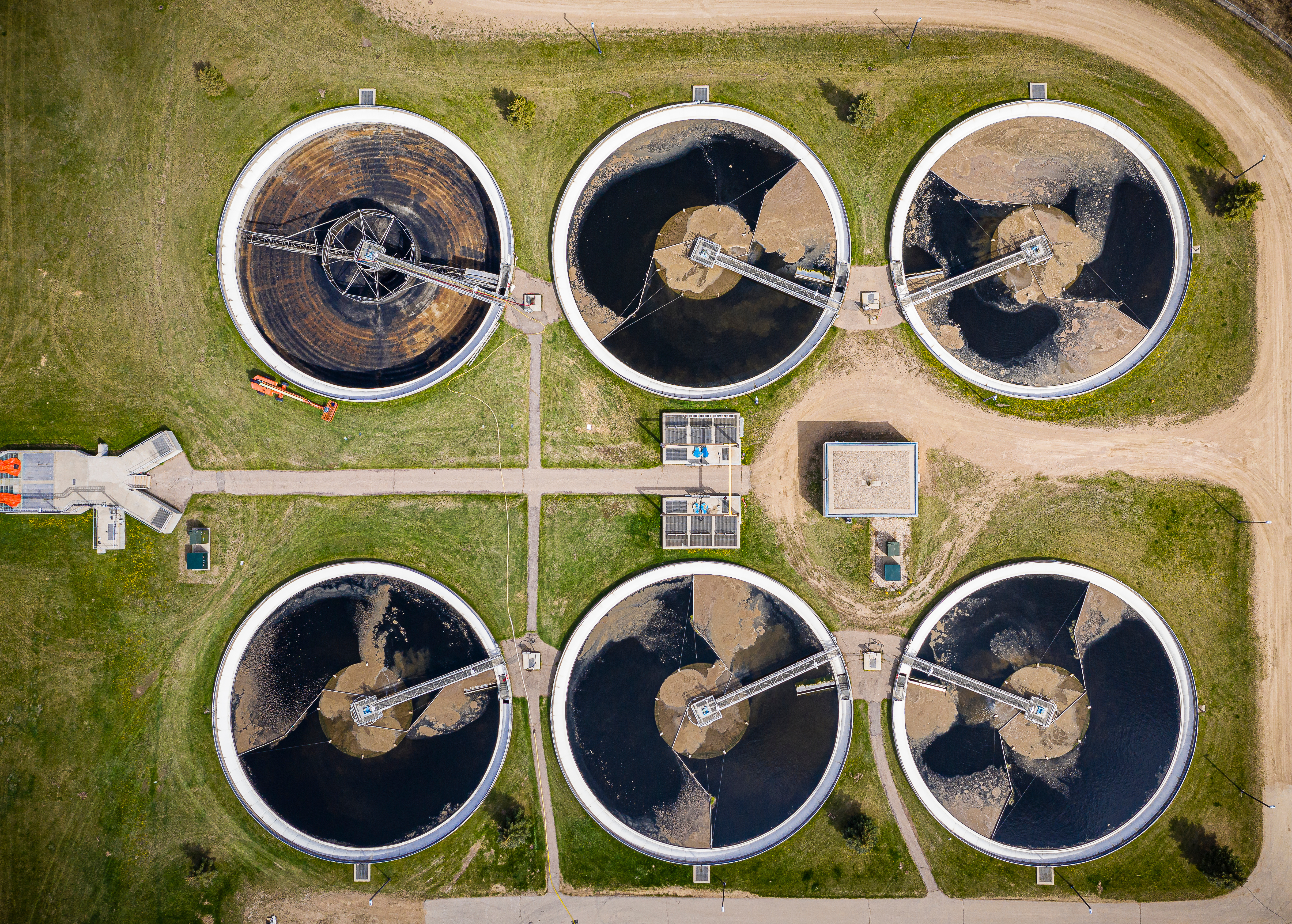 Aerial view of a wastewater treatment plant featuring six circular sedimentation tanks.